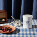 Metabolics Citrate Malate Supplement container on a table with a plate of fruits and a jar, against a dark curtain background.