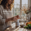 Woman taking a supplement capsule with a Metabolics container on a wooden table.